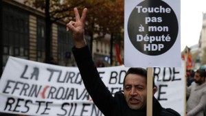 A man holds a placard reading "Don't touch my HDP (pro-Kurdish Peoples' Democratic Party) MP" and flashes a victory sign during a protest in Paris on November 5, 2016, following the arrest of the two co-leaders of Turkey's main pro-Kurdish party. An Istanbul court today ordered the imprisonment of nine staff from the opposition Cumhuriyet newspaper, in an intensifying crackdown a day after the leaders of the country's main pro-Kurdish party were also jailed. Nine MPs from the opposition pro-Kurdish People's Democratic Party (HDP), including its co-leaders Selahattin Demirtas and Figen Yuksekdag, were also jailed ahead of trial by the courts on November 4 on terror charges. / AFP PHOTO / GEOFFROY VAN DER HASSELT